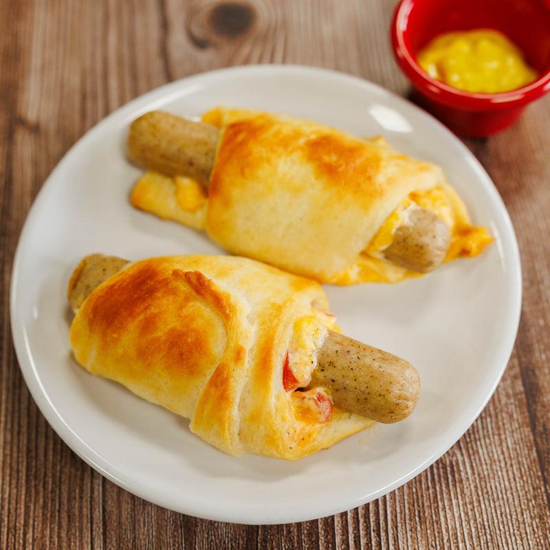 Two cheesy sausage rolls on a white plate